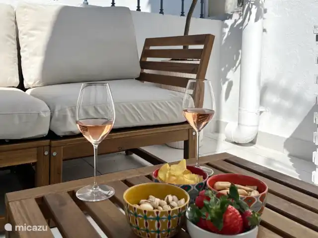Privé terras met tweezits bankje, tafel en stoel.